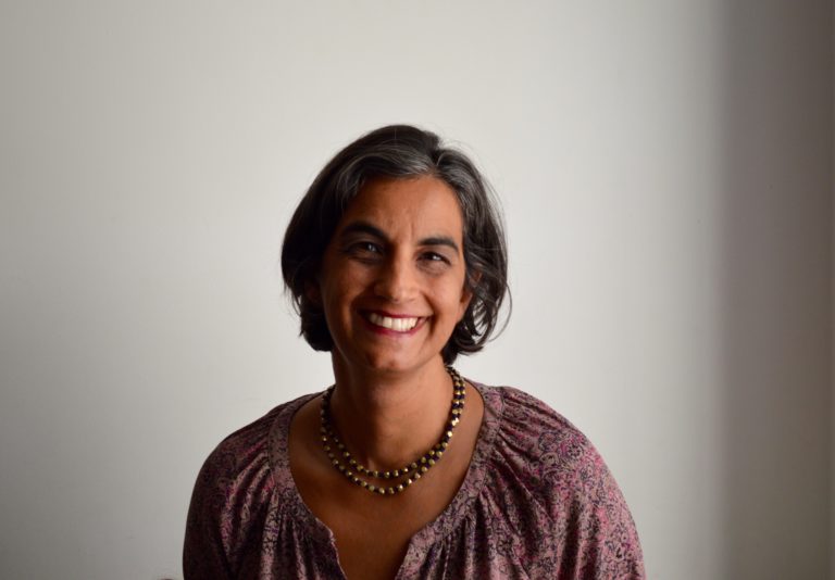 A South Asian woman with chin-length hair in her 40s and a floral blouse. 