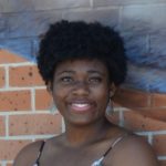 A Black woman in her early 20s with black natural hair in a small afro.