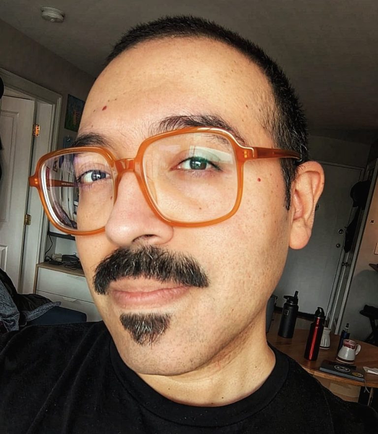 A Mexican-American man, 40 years old, with facial hair.