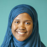 A Black woman, smiling, with a turquoise Islamic headscarf