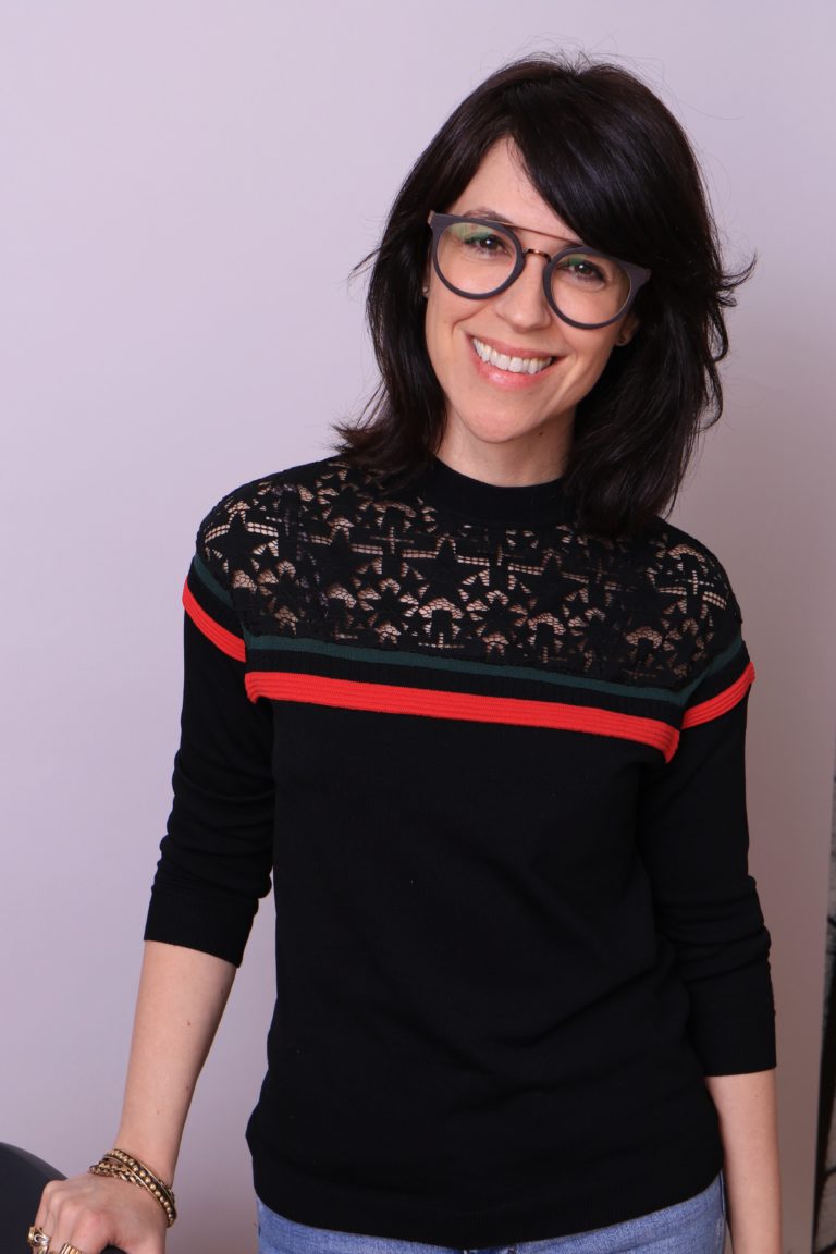 A smiling white woman in her 40's with dark hair and cool glasses. 
