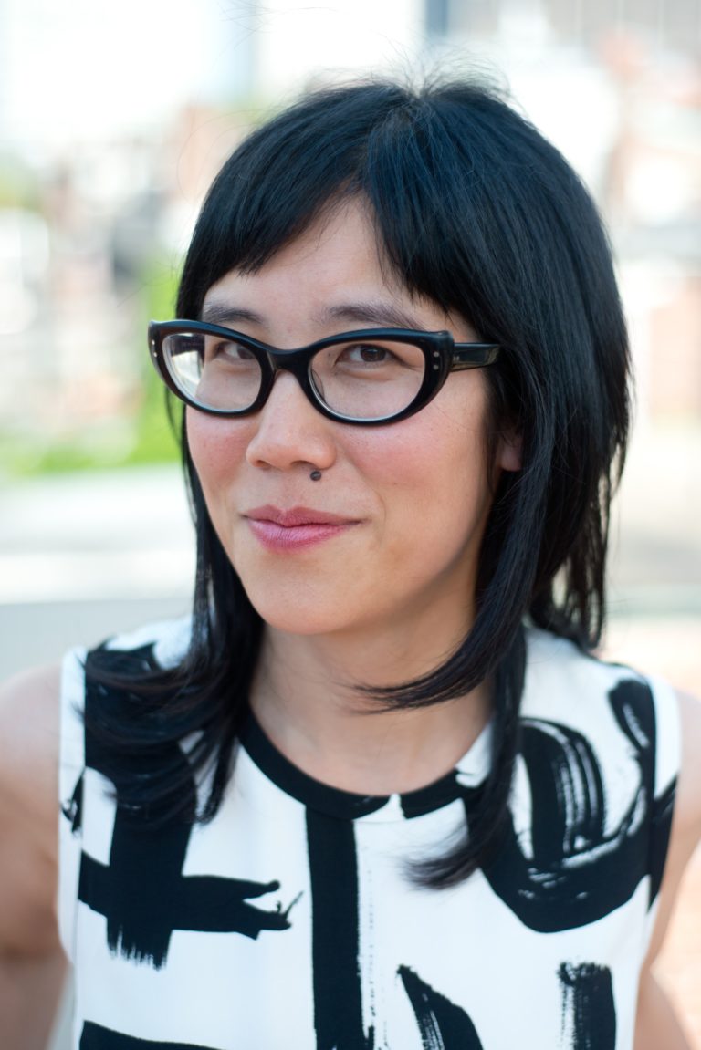 An East Asian woman with shoulder length black hair and thick black glasses.