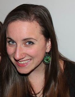 A white woman in her 30s, with a nose ring, light brown hair, and green eyes.