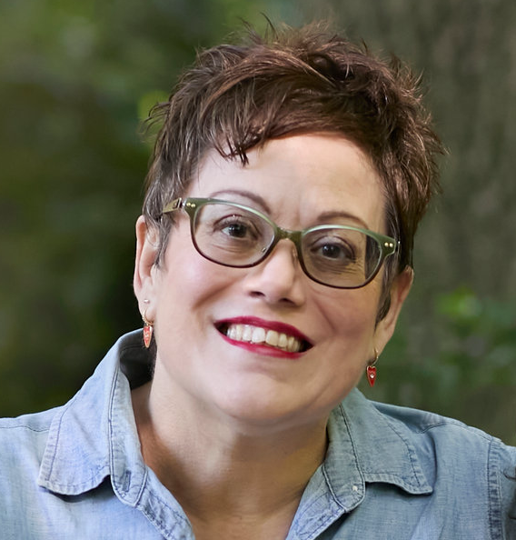 A middle-aged brunette woman with short hair and red lipstick wearing glasses with light green top rims shading to brown bottom rims.